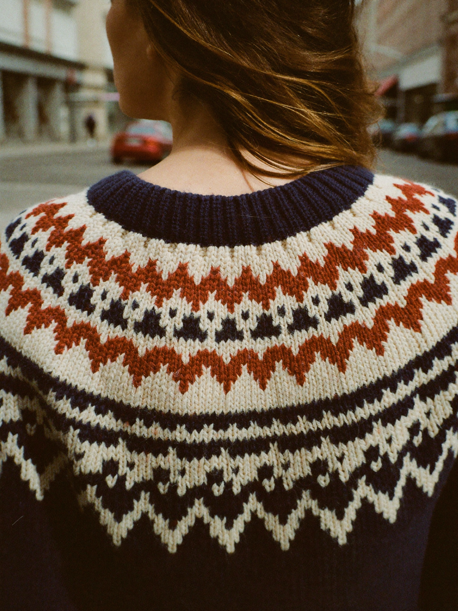 Close back view of a Fair Isle yoke knit sweater in cream, rust and navy