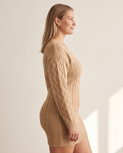 Cable Knit Mini Dress — three-quarter view, on a warm off-white studio backdrop