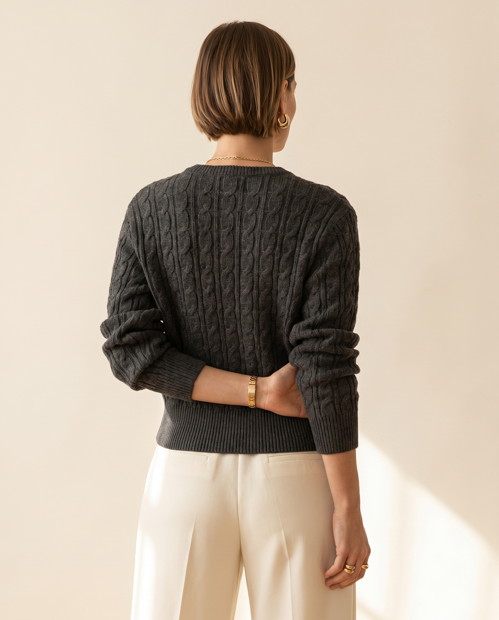 Cable V-Neck — back view, on a warm ivory studio backdrop