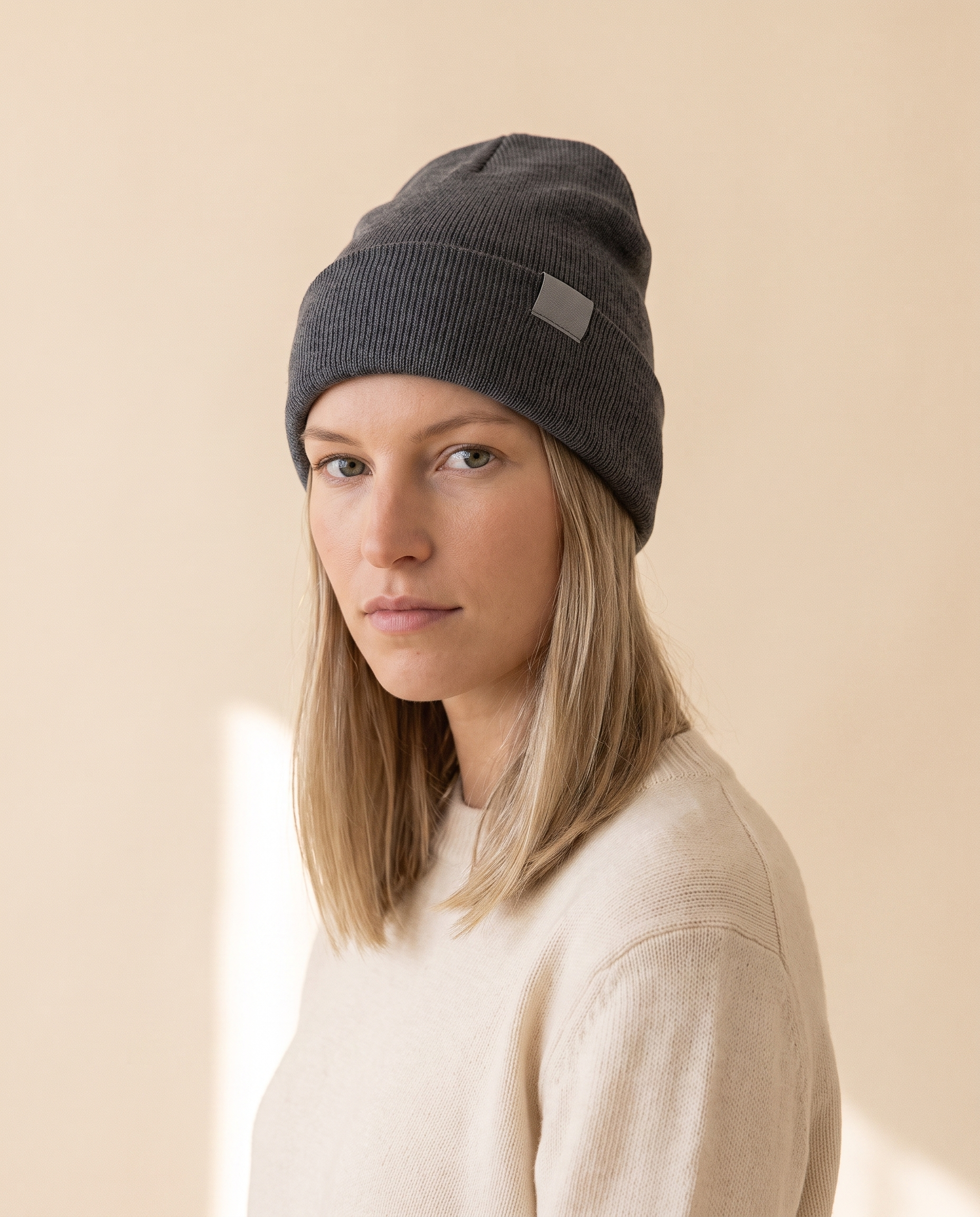 Label Cuff Beanie on a pale sand studio backdrop