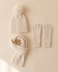 Hat, Scarf and Glove Set flat lay on a pale sand background